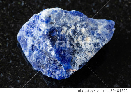 sample of raw sodalite mineral on black granite 129481821