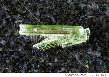 sample of raw zoisite crystals on black granite 129481871