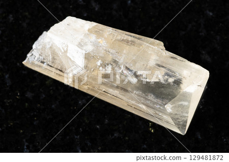 sample of rough danburite mineral on black granite 129481872