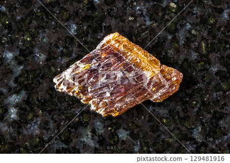 sample of rough rutile mineral on black granite 129481916