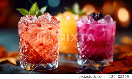 Three colorful cocktails with ice, fruit, and mint garnishes served in clear glasses with autumn decor Three colorful cocktails with ice, fruit, and mint garnishes served in clear glasses with autumn decor 129482209