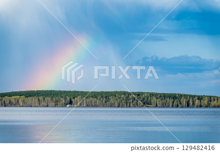 Rainbow over Blue lake with cloudy sky Rainbow over Blue lake with cloudy sky 129482416