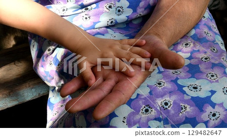 Closeup great-grandchild hand atop hand palm of great-grandmother 129482647