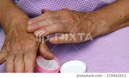 Old lady hands apply moisturizer at her elder skin 129482652
