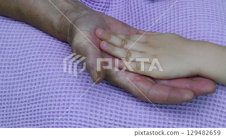 Wrinkled palm of hand and kid hand touching each other. Closeup 129482659