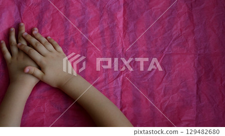 Closeup of crossed child hands on pink background with copy space Closeup of crossed child hands on pink background with copy space 129482680