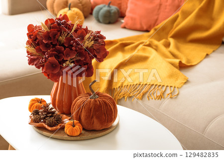 Thanksgiving living room decor with a coffee table, pumpkins and a floral arrangement. Thanksgiving living room decor with a coffee table, pumpkins and a floral arrangement. 129482835