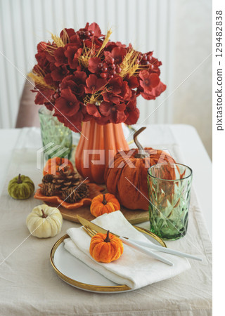 Thanksgiving table setting with decorative pumpkins, candles and string lights on white wooden table Thanksgiving table setting with decorative pumpkins, candles and string lights on white wooden table 129482838