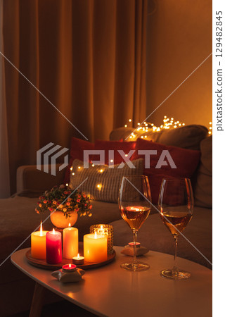 Cozy evening scene with candles, wine glasses and warm lighting. 129482845