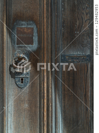 Aged wooden door with Ornamental keyhole and knocker, Antique wooden gate of Holy trinity church. 129482953