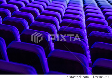 Rows of vibrant theater seats illuminated by artistic blue light 129483055