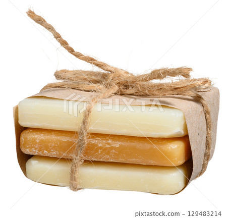 Three pieces of natural soap are wrapped in craft paper and tied with thick twine, tied in a bow. Isolated background 129483214