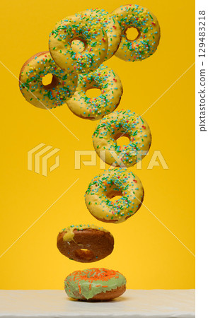Yellow glazed donuts, each decorated with multi colored sprinkles. Yellow glazed donuts, each decorated with multi colored sprinkles. 129483218
