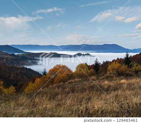 Foggy early morning autumn mountains scene. Peaceful picturesque traveling, seasonal, nature and countryside beauty concept scene. Carpathian Mountains, Ukraine. 129483461