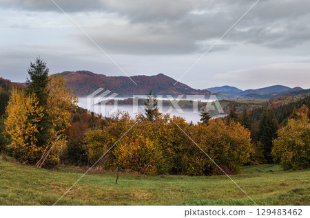 Foggy early morning autumn mountains scene. Peaceful picturesque traveling, seasonal, nature and countryside beauty concept scene. Carpathian Mountains, Ukraine. Foggy early morning autumn mountains scene. Peaceful picturesque traveling, seasonal, nature and countryside beauty concept scene. Carpathian Mountains, Ukraine. 129483462