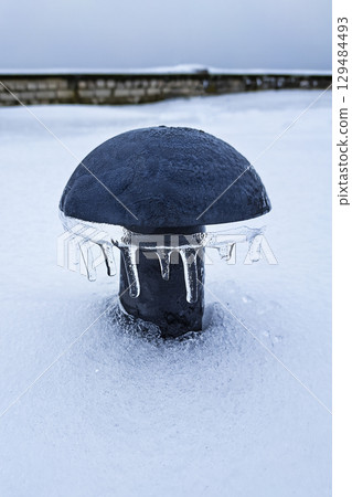 Black plastic air vent, mushroom shaped air vent in winter in snow and icicles on the roof of a 129484493