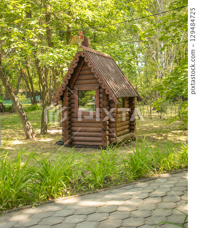 Vintage installation in the park. A small log fairy-tale house, vertical. 129484725