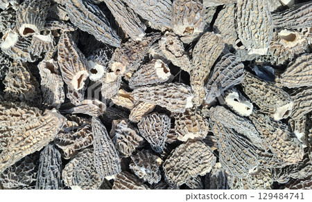 Close-up view of dried morel mushrooms reveals their unique, textured surfaces. These mushrooms are often sought after for culinary use due to their distinctive flavor. Close-up view of dried morel mushrooms reveals their unique, textured surfaces. These mushrooms are often sought after for culinary use due to their distinctive flavor. 129484741