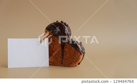 White paper note template greeting card mockup Delicious fresh croissant topped with Dark chocolate flavor Ganache. Creation unique heart shape bakery. Puff pastry holiday love gift present idea 129484768