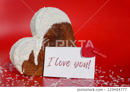 I LOVE YOU saying on paper holiday card Valentine's day celebration Heart shaped coconut flavor croissant on red background with copy space. Puff pastry new trendy sweet dessert bakery. Creamy dough 129484777