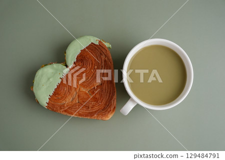 Green tea Matcha latte cappuccino beverage Morning breakfast gift idea Heart shaped pistachio croissant on green background with copy space. Puff pastry trendy sweet dessert bakery. Creamy dough 129484791