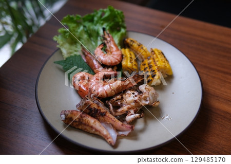 Grilled seafood corn Mixed corn and seafood barbecue. Grilled corn and chicken on the barbecue. Grilled prawns sizzle on the barbecue when the prawn is flipped. 129485170