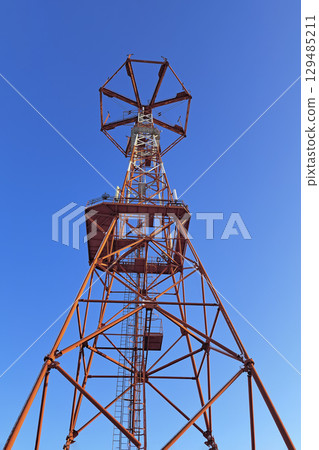 The communication tower stands against the sky with a bottom-up view. Close-up 129485211