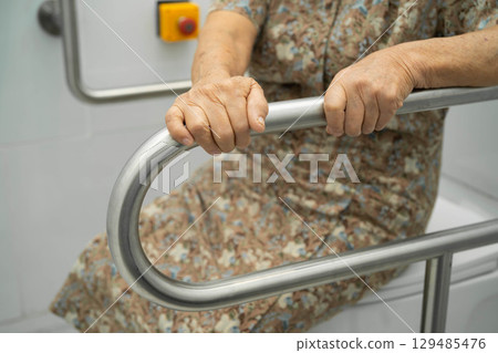 Asian elderly woman patient use handrail safety in toilet support rail in bathroom. Asian elderly woman patient use handrail safety in toilet support rail in bathroom. 129485476