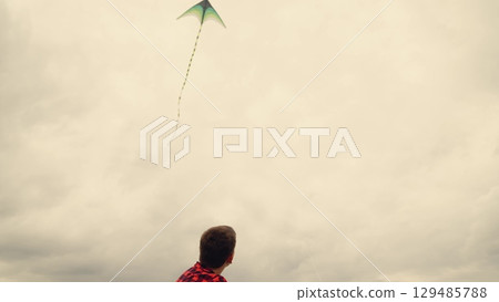 Carefree kids launching a kite, Imagination takes flight, Simple joys of childhood, Boys in matching shirts play, Green kite against cloudy sky, Childhood memories in the meadow, Adventures in an open 129485788