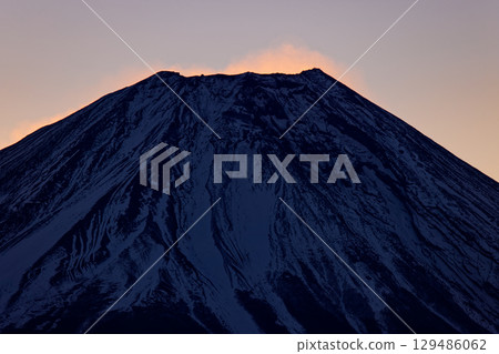 Mount Fuji with snow smoke rising just before sunrise, seen from Asagiri Plateau and Amagatake 129486062
