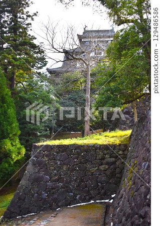 The stone walls of the Matsue Castle, a national treasure, with its castle tower towering against the winter sky 129486586