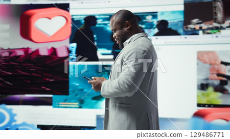 Happy person uses phone, doing engagement with multimedia content, sending likes. Joyous man browsing social networks feed on smartphone in front of dashboard featuring videos, camera A Happy person uses phone, doing engagement with multimedia content, sending likes. Joyous man browsing social networks feed on smartphone in front of dashboard featuring videos, camera A 129486771
