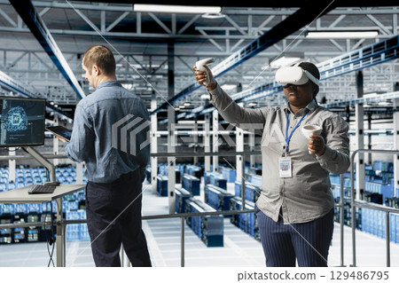 Teamworking server farm programmers using VR headset, running AI simulations. African american woman and coworker in data center using virtual reality technology to visualize neural networks Teamworking server farm programmers using VR headset, running AI simulations. African american woman and coworker in data center using virtual reality technology to visualize neural networks 129486795