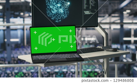 Isolated screen laptop next to elevated industrial data center control station display showing AI visualization. Chroma key notebook device in server farm displaying neural network diagnostics 129486808