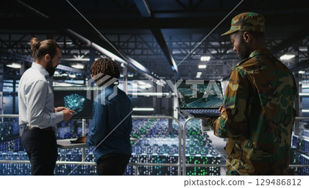 Military technician in data center monitoring warfare drone telemetry on laptop dashboard. IT specialist in army server room using tactical interface on notebook to support aerial operations Military technician in data center monitoring warfare drone telemetry on laptop dashboard. IT specialist in army server room using tactical interface on notebook to support aerial operations 129486812