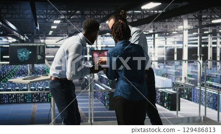 Worried workers trying to fix hacked infrastructure systems. Panicked engineers in data center react to ransomware warning on laptop screen, scrambling to launch emergency response protocol, Worried workers trying to fix hacked infrastructure systems. Panicked engineers in data center react to ransomware warning on laptop screen, scrambling to launch emergency response protocol, 129486813