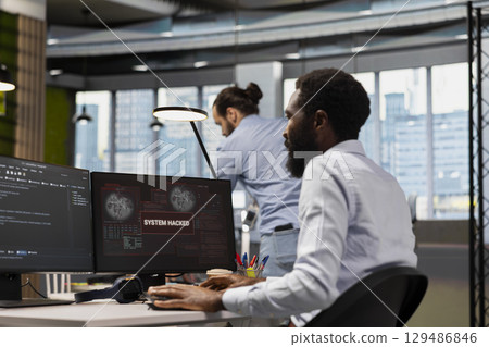 Computer scientist blocking network intrusion affecting office equipment. IT employee responding to live cyberattack warning popup on PC, neutralizing hacker breach in tech startup workspace 129486846