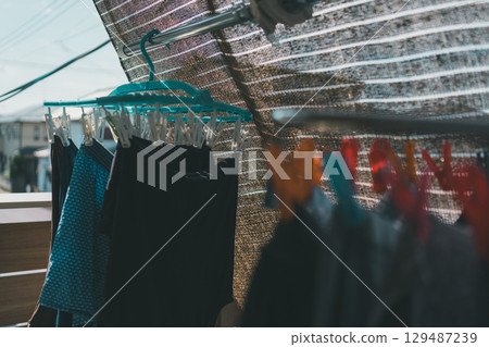 A family drying laundry in a small space inside a sunshade 129487239