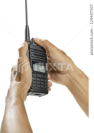Closeup view of a human hand holding a black walkie talkie radio communication device isolated over a white background Closeup view of a human hand holding a black walkie talkie radio communication device isolated over a white background 129487507