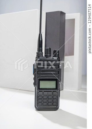 Closeup view of a black walkie talkie radio communication device on the table with a white background Closeup view of a black walkie talkie radio communication device on the table with a white background 129487514
