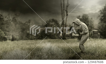 Pocong on the field at night. A traditional ghost from Indonesia that takes the form of a human wrapped in a shroud or winding sheet. Concept of Halloween Pocong on the field at night. A traditional ghost from Indonesia that takes the form of a human wrapped in a shroud or winding sheet. Concept of Halloween 129487686