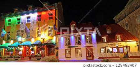 Tourists enjoying walking in Old Quebec City streets, including colourful illuminated restaurants 129488407