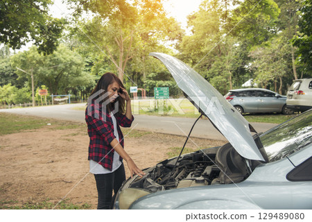 Asian women use phone call insurance agent for help car problem breakdown. Woman calling mechanic car service technician support fix repair driving. Transportation vehicle accident emergency problem 129489080