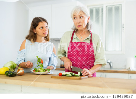 Senior woman and her daughter cooking salad at home Senior woman and her daughter cooking salad at home 129489087