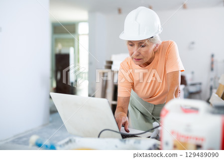 Woman using laptop in apartment under reconstruction Woman using laptop in apartment under reconstruction 129489090