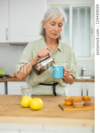 Old woman pouring coffee, having breakfast at home Old woman pouring coffee, having breakfast at home 129489099