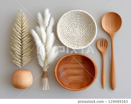 Rustic wooden utensils, woven basket, dried botanicals arranged elegantly on neutral surface, evoking warm, minimalist kitchen aesthetic 129489163