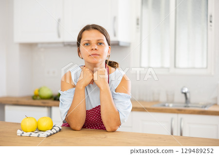 Young housewife in apron posing in modern kitchen Young housewife in apron posing in modern kitchen 129489252