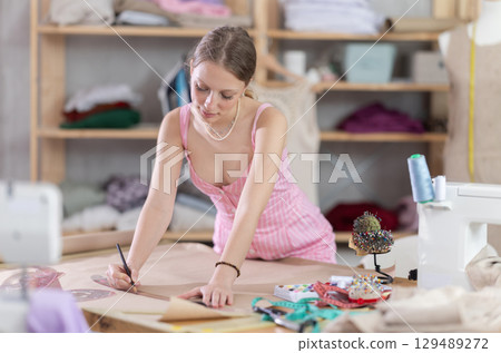 Woman tailor drawing on paper in workshop 129489272