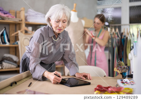 Mature Fashion Designer Drawing Mockup On Tablet Mature Fashion Designer Drawing Mockup On Tablet 129489289